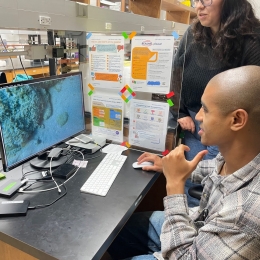 Caves Lab PhD student Bryce Barbee and research technician Miya Ball observe the behavior of cleaner shrimp on a typical video brought back from their field site in Curaçao.